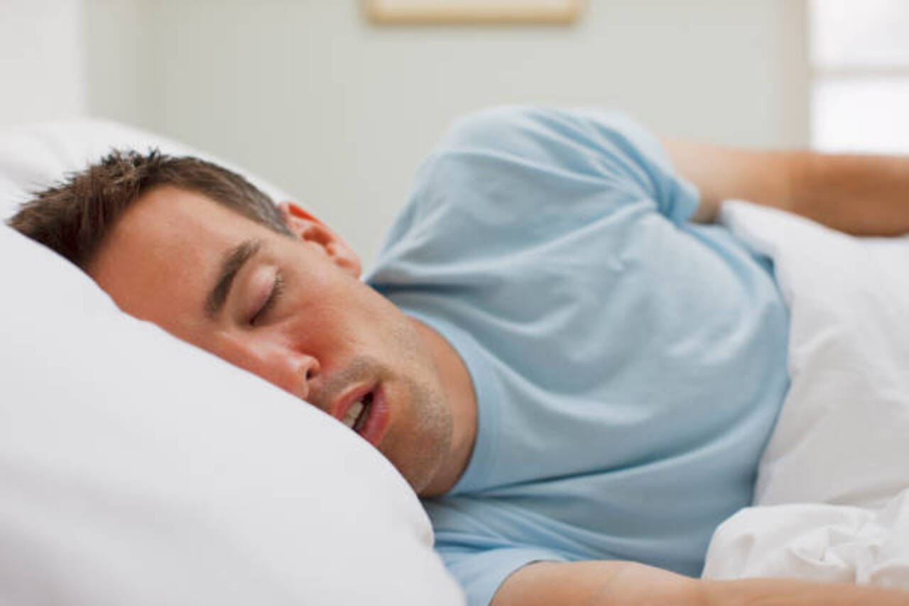 Man sleeping on his side as a home remedy for sleep apnea.