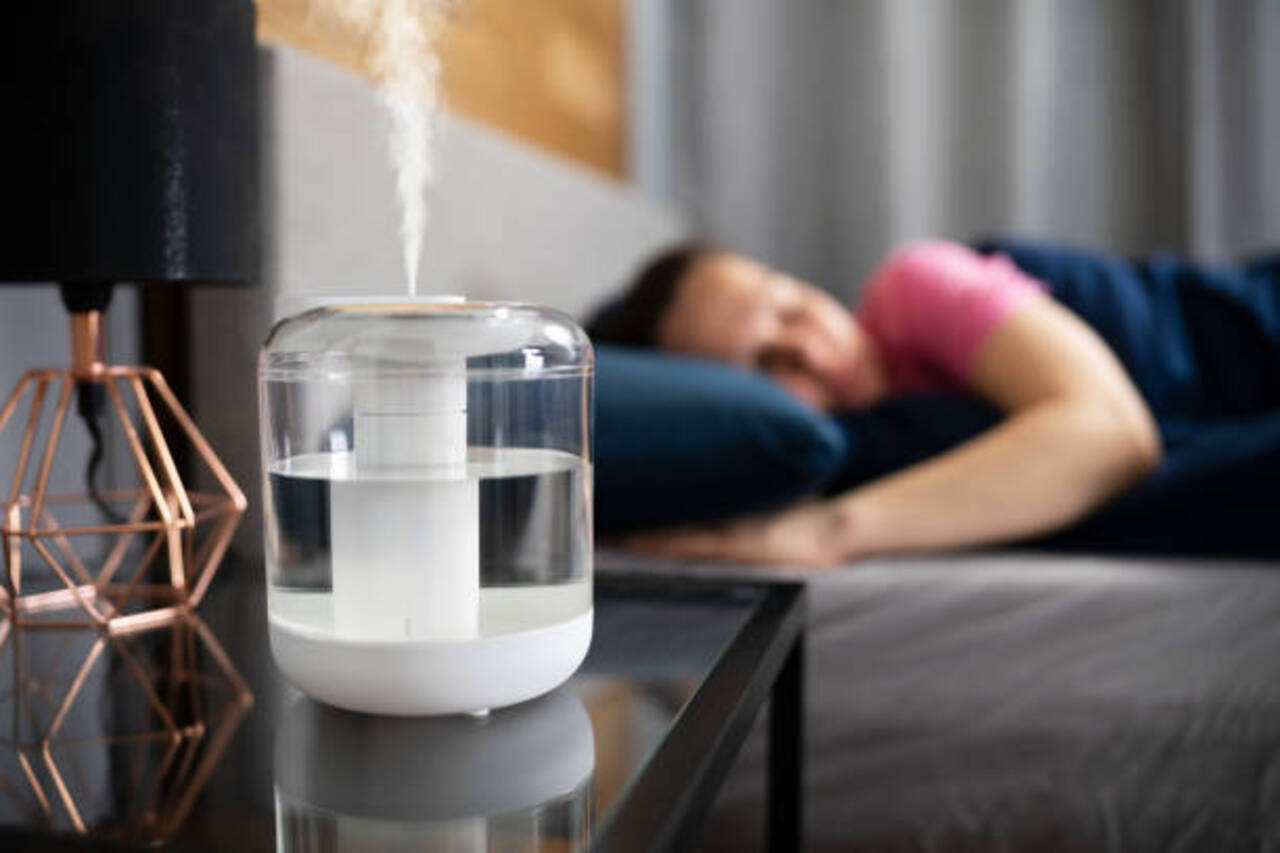 Humidifier running near a sleeping person for better air.