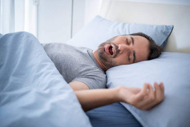 Man sleeping with mouth open, showing how sleep apnea impacts rest.