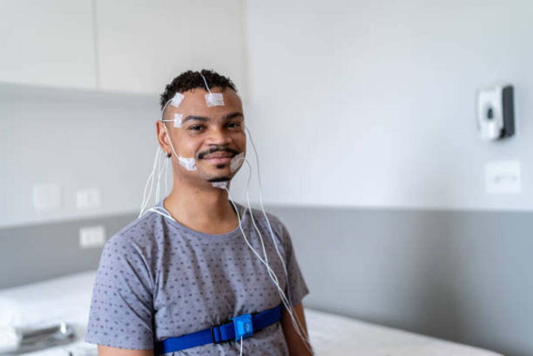 Man undergoing a sleep study with sensors on his face.