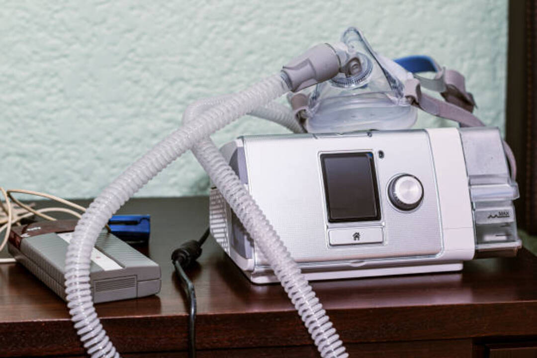 CPAP machine with mask on bedside table for sleep aid.
