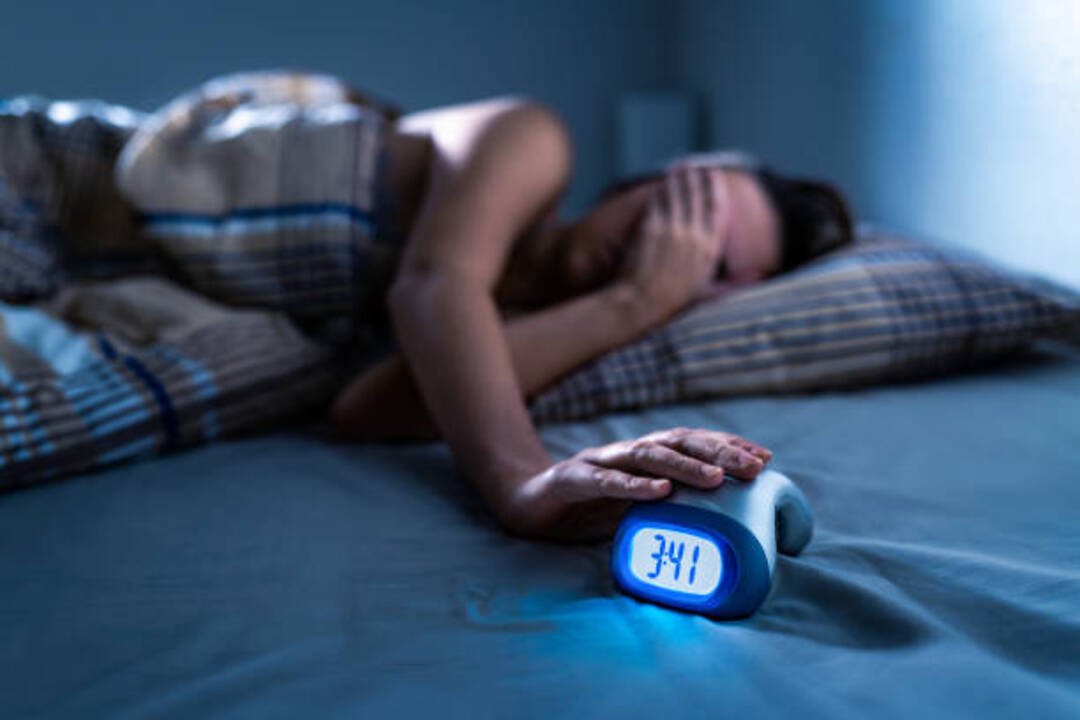Person suffering from insomnia looking at the clock