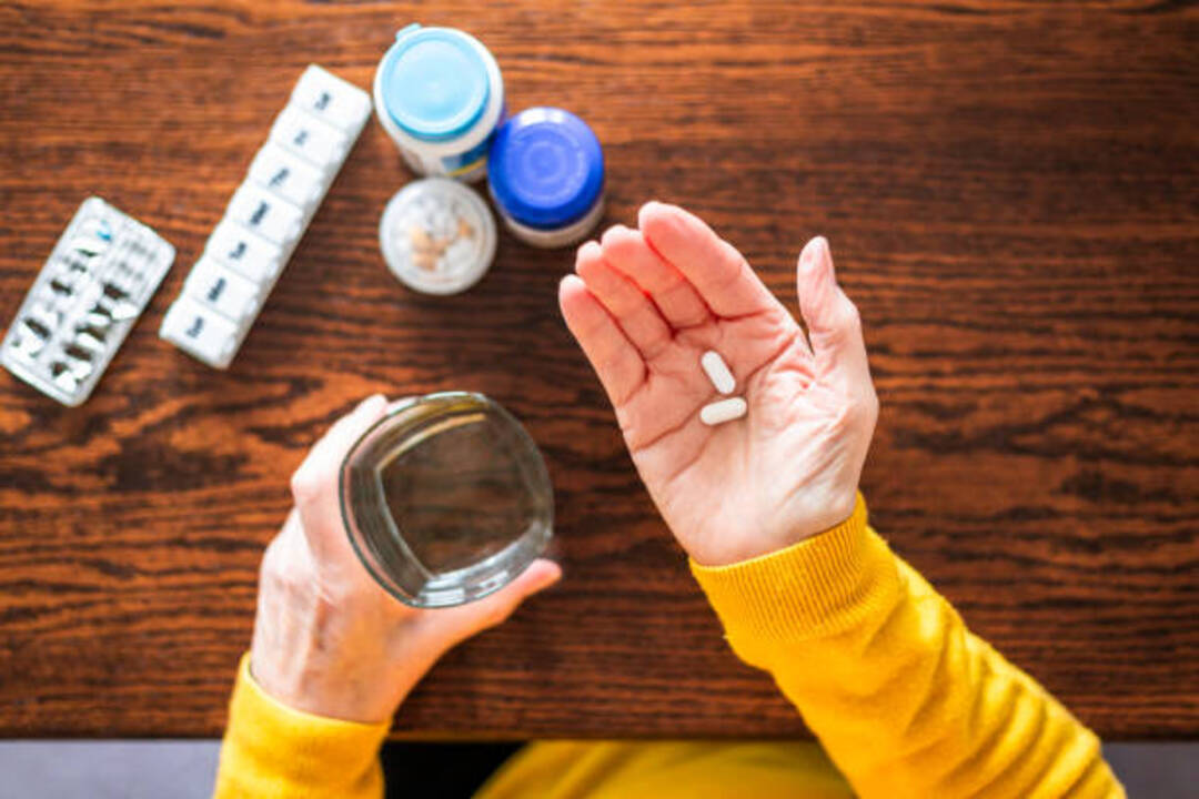Person holding medication with a glass of water for sleep.