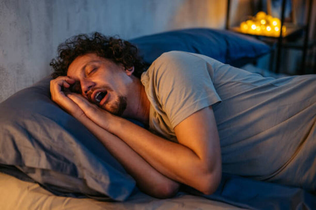 Man snoring loudly while sleeping in bed.