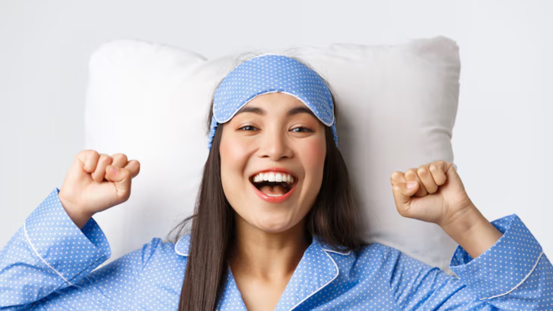 Woman smiling and stretching in bed after a restful sleep.