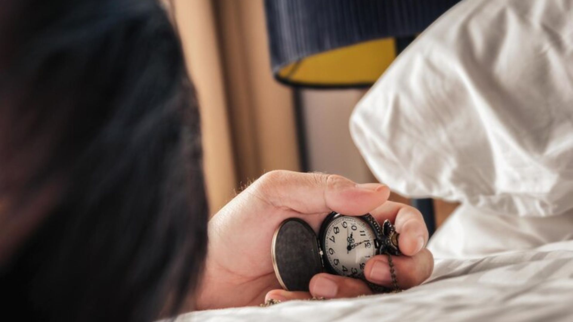Person holding a pocket watch, removing clocks from the bedroom.