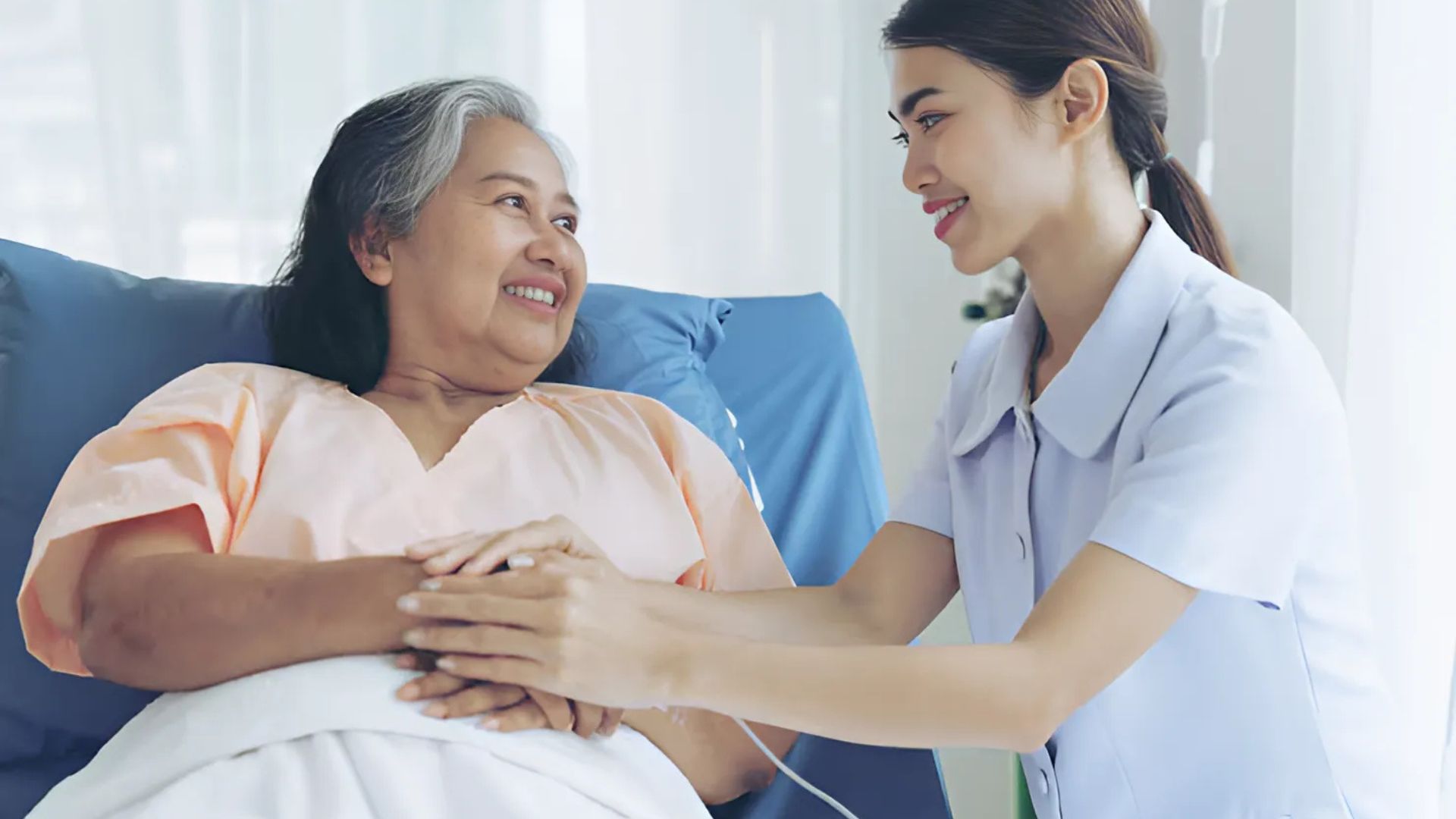 A nurse offering care and comfort to a patient in bed.