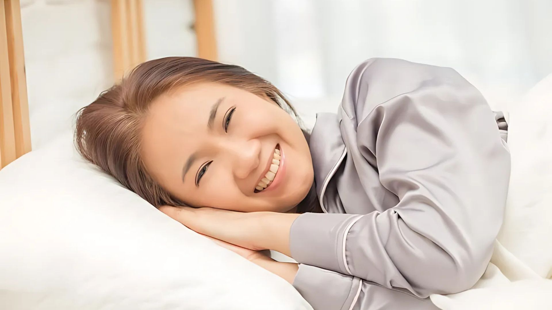 A woman smiling happily while resting in bed.
