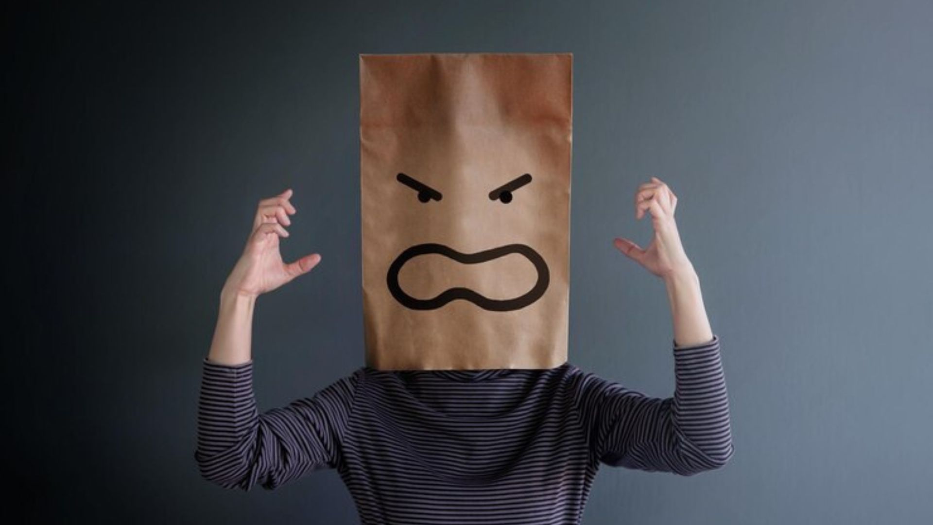 Person with angry expression, wearing a paper bag mask, representing stress.