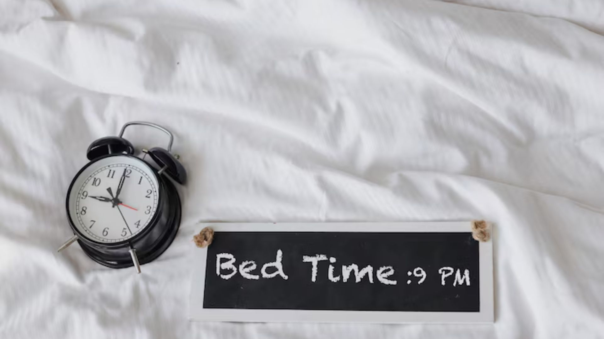 Alarm clock and sign showing bedtime at 9 PM for better sleep.