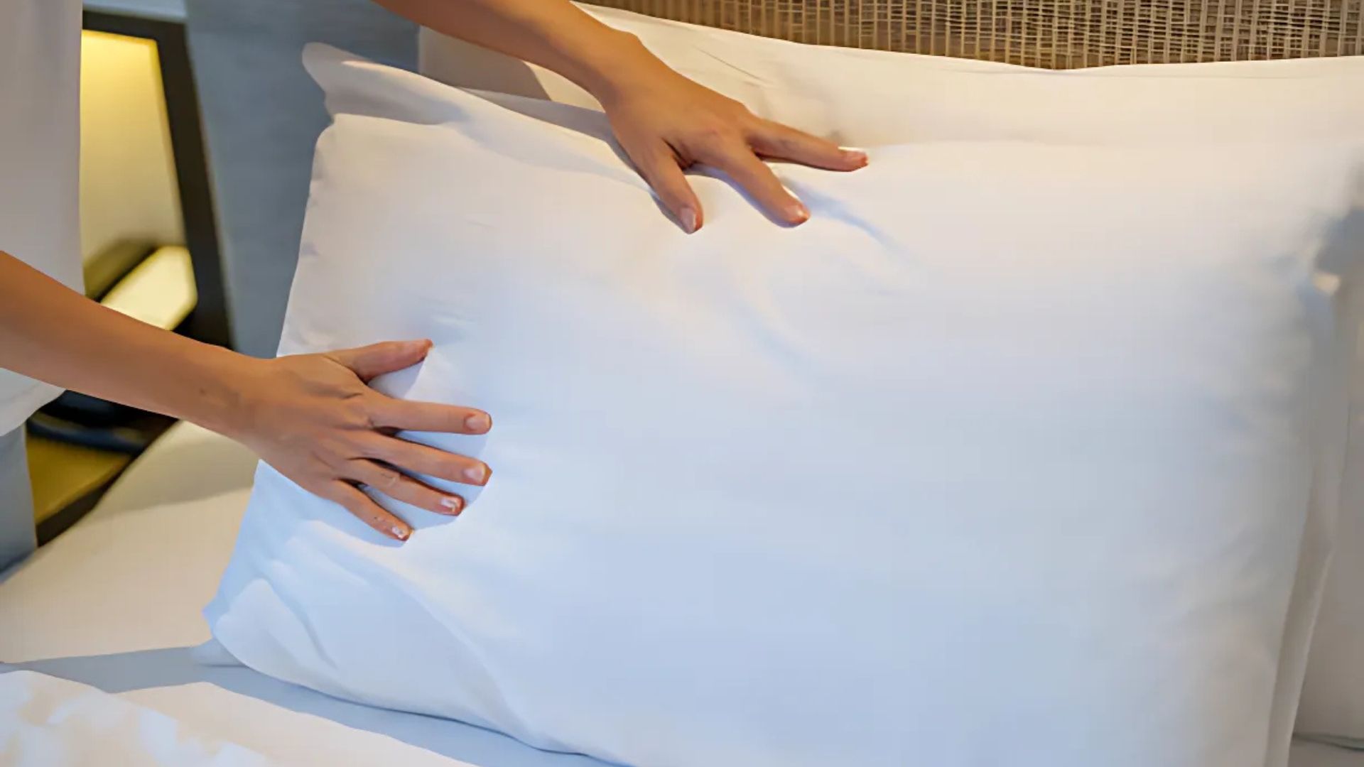 A person adjusting a pillow for optimal sleep comfort and support.
