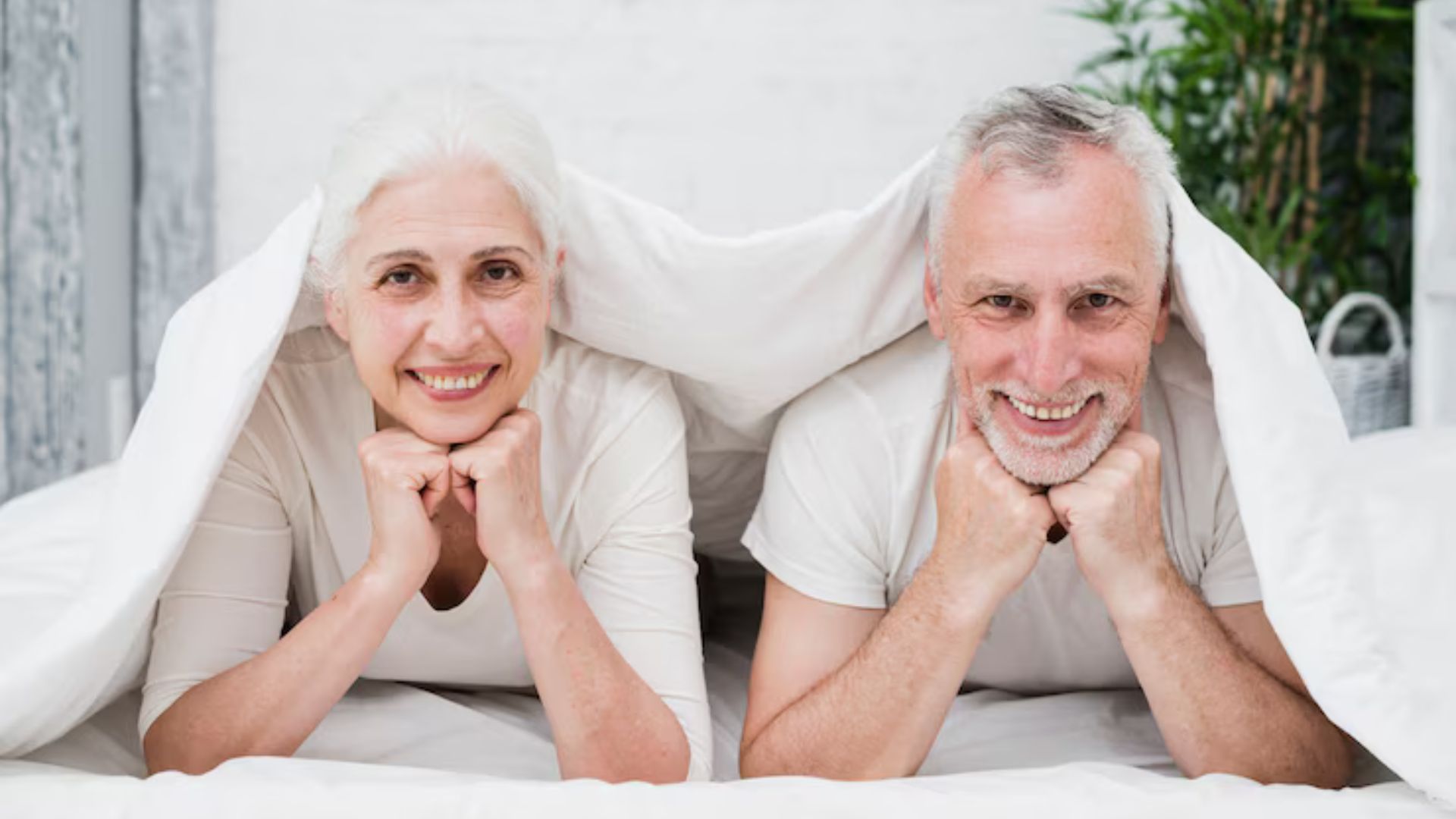 Happy elderly couple lying in bed, taking the first step to better sleep.
