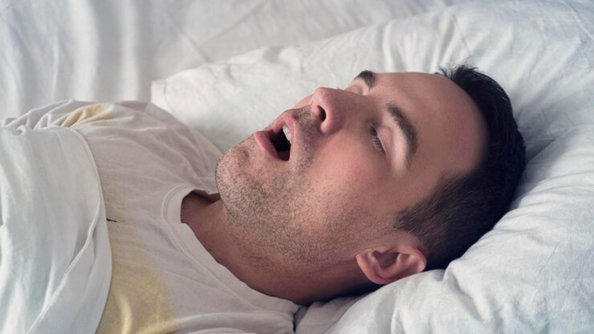 Man sleeping with an open mouth, likely snoring during rest.
