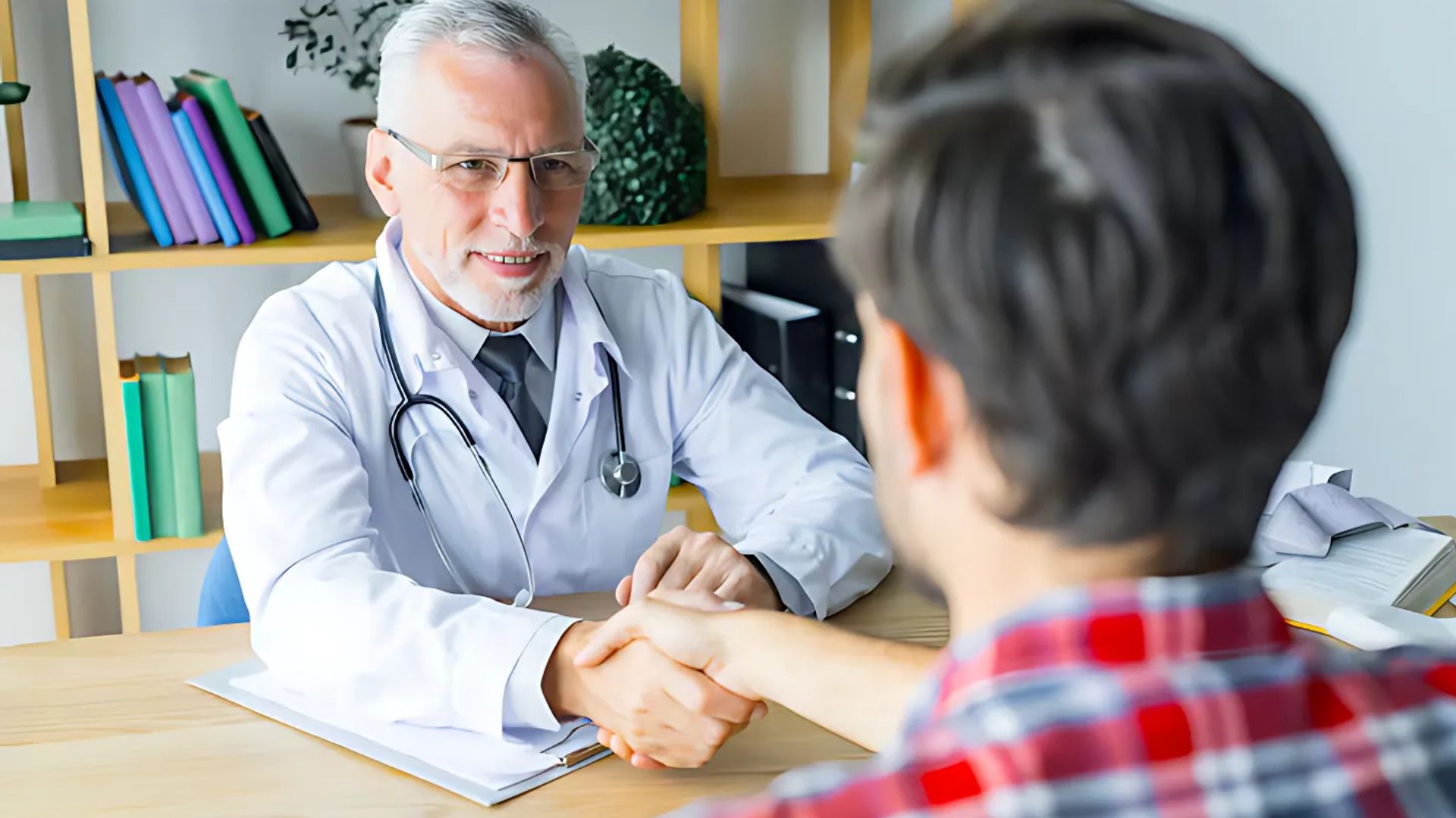 Doctor shaking hands with a patient in a consultation room.