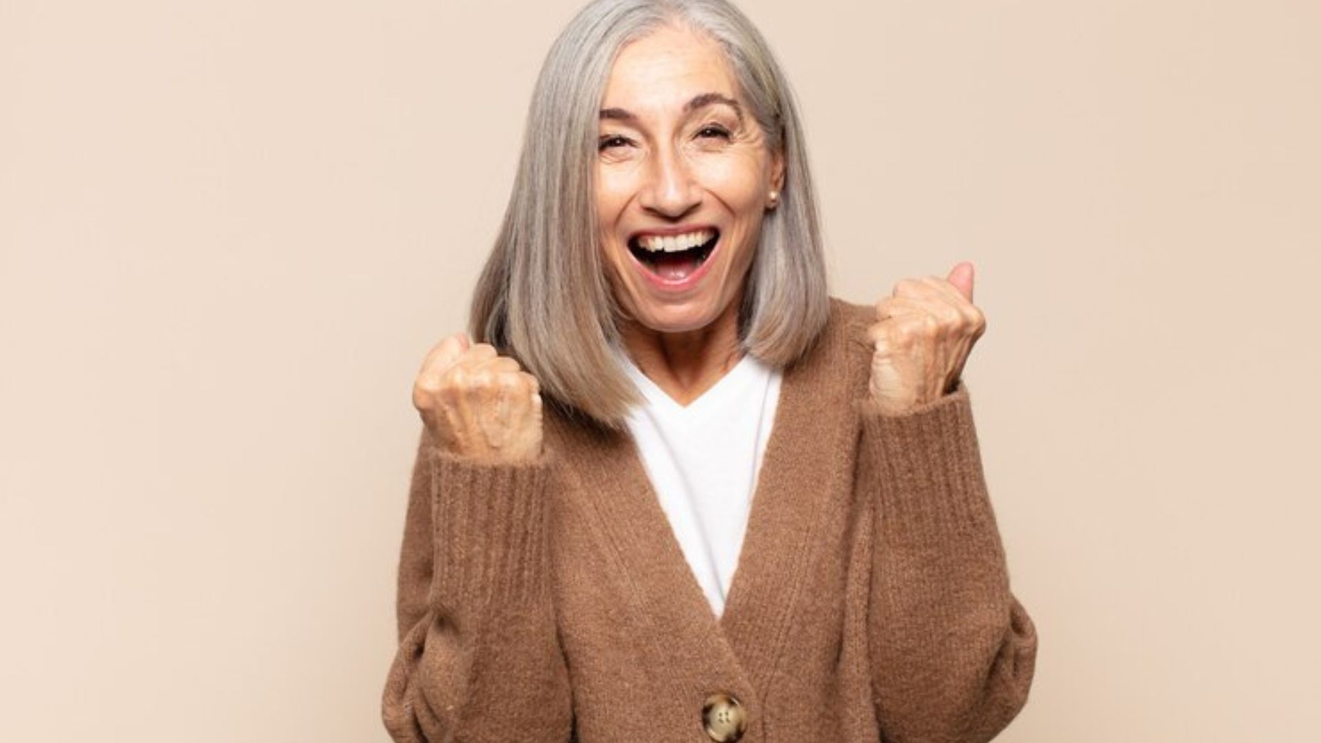 Older woman smiling and celebrating with a raised fist.