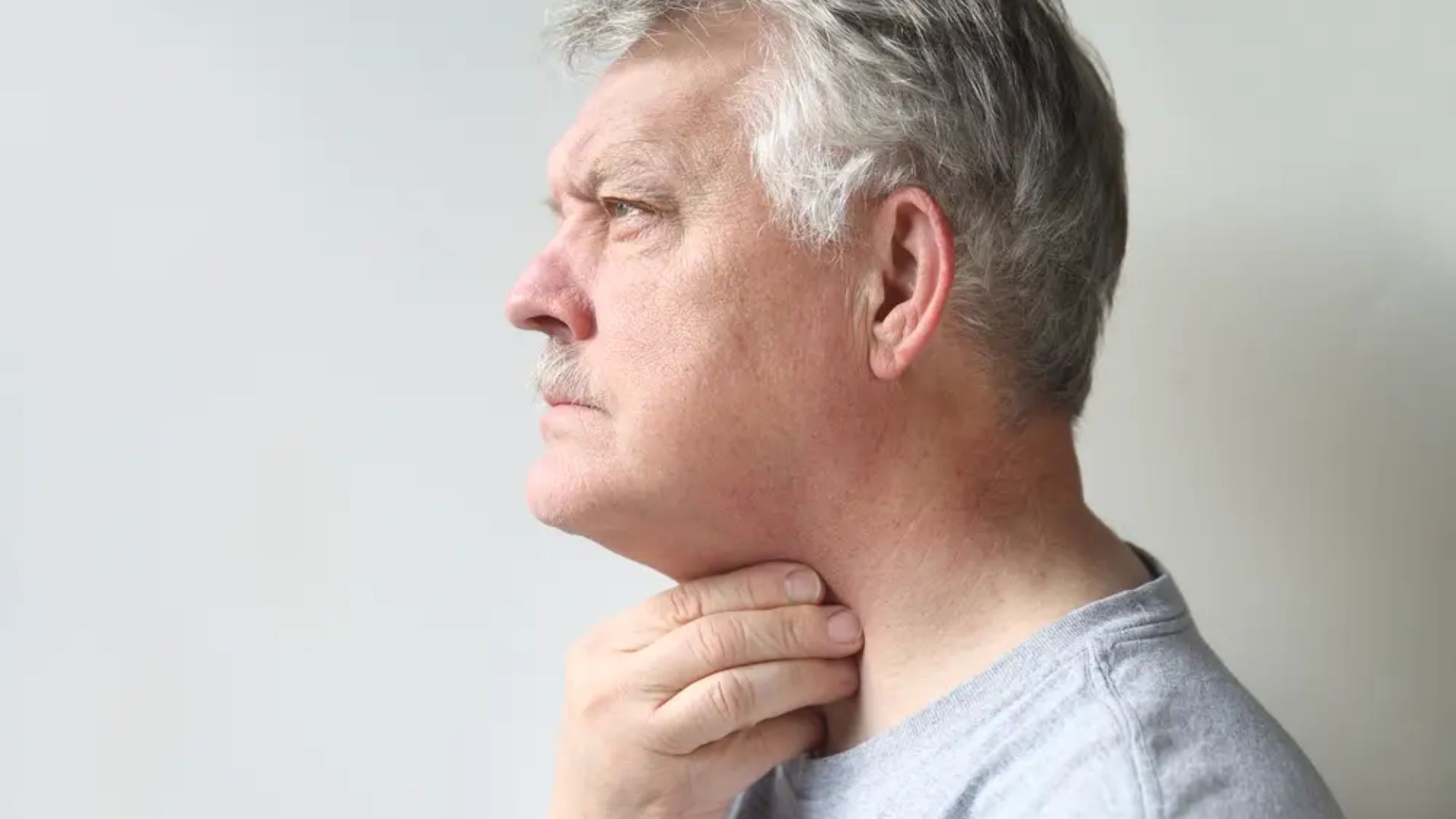 Man touching throat showing dry mouth sleep apnea symptom