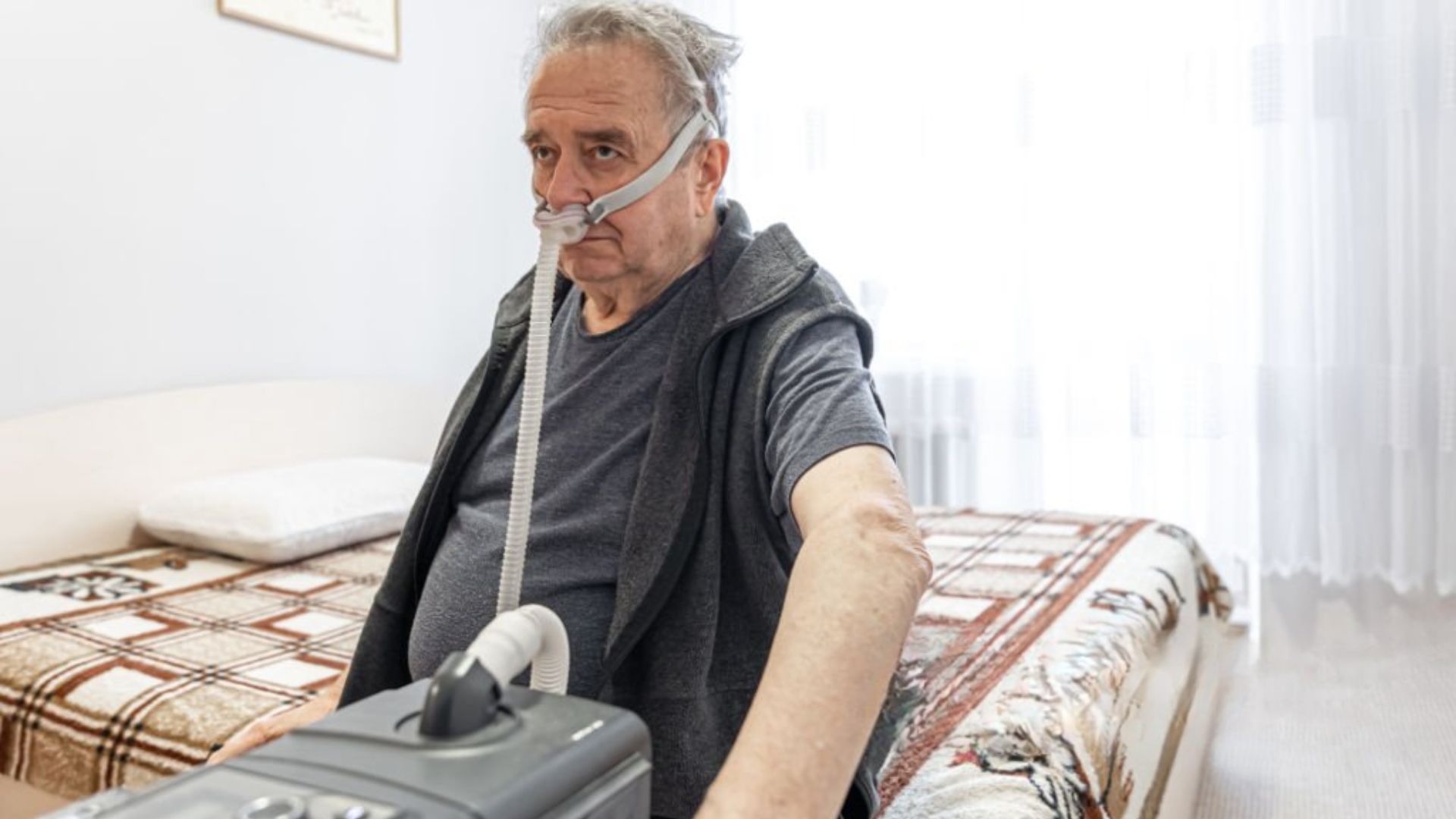 Senior using CPAP device at home for improved sleep nightly.