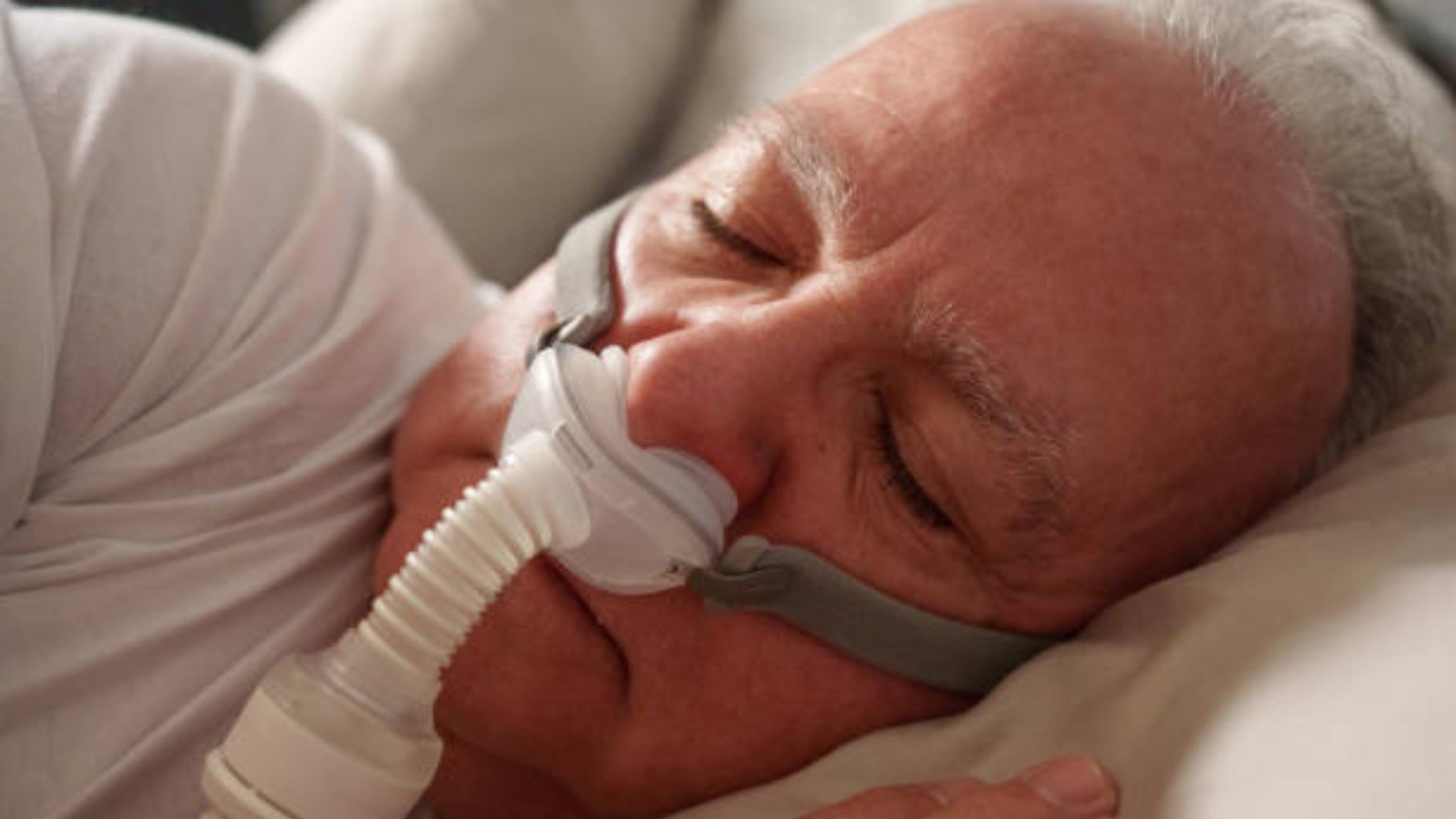 Senior sleeping with CPAP mask for sleep apnea therapy